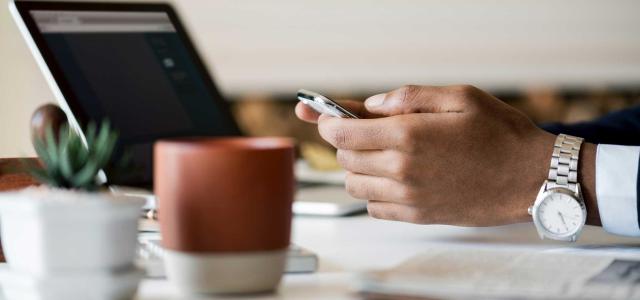 Hands with phone and laptop
